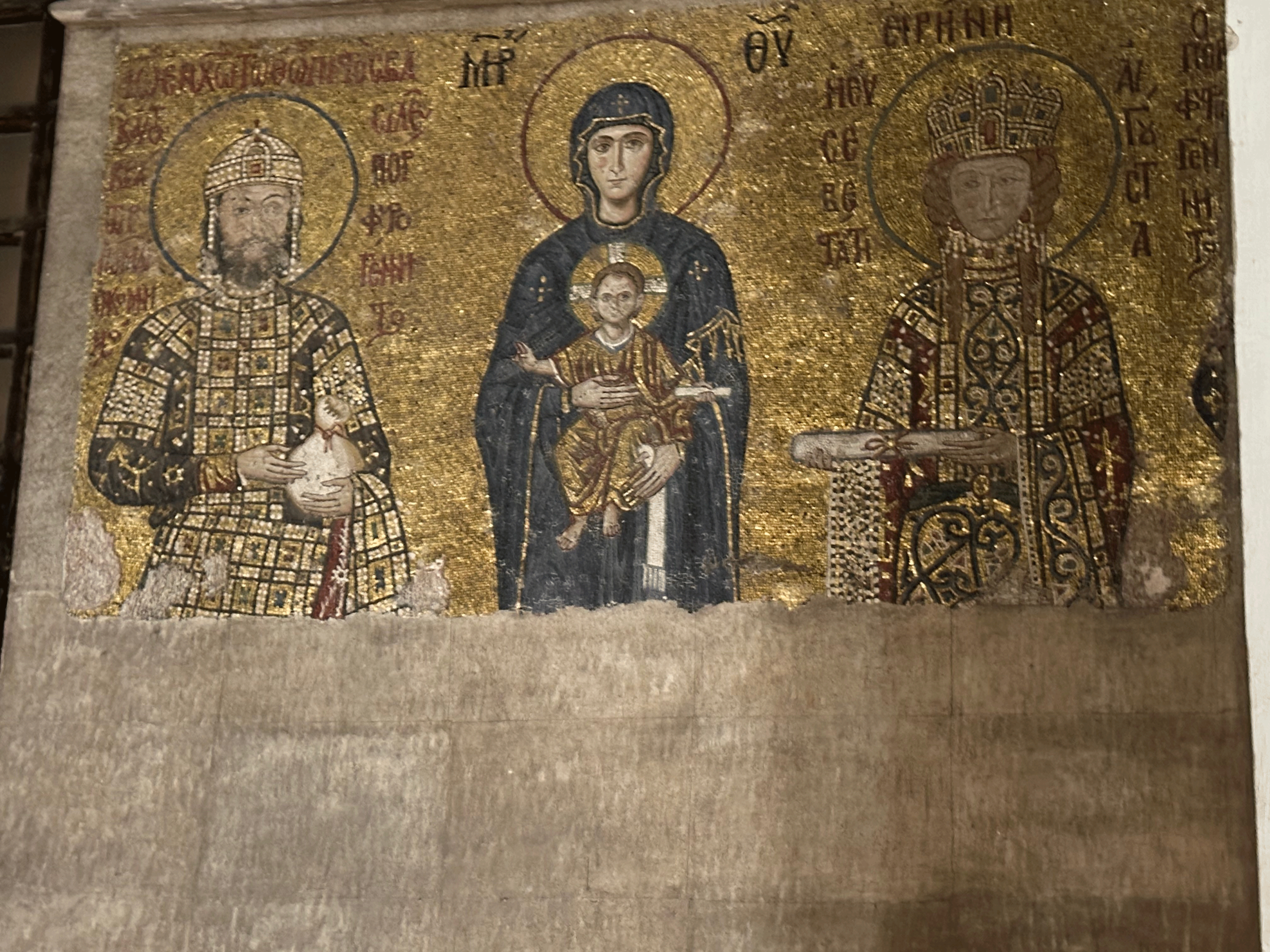A historic mosaic depicting the Virgin Mary holding the infant Jesus, flanked by two Byzantine emperors, featuring intricate patterns and gold accents.
